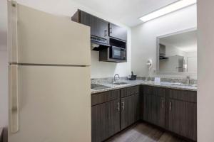 a kitchen with wooden cabinets and a refrigerator at Suburban Studios Cookeville in Cookeville