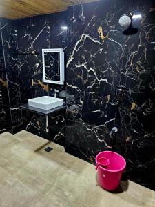 a black marble bathroom with a sink and a bucket at Jjs PARK INN in Chennai