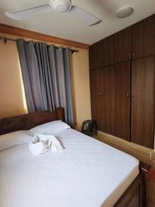 una camera da letto con letto, lenzuola bianche e armadi in legno di Fair deal Apartment a Mombasa