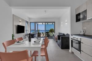 a kitchen and living room with a white table and chairs at Beachfront Apartment Beach Makarska Residence Srzić in Makarska