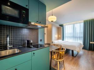 a kitchen with a sink and a bed in a room at Aparthotel Adagio Access Rouen Centre Cathédrale in Rouen