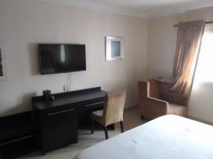 um quarto com uma secretária, uma televisão e uma cadeira em St Theresers apartment Lodge 2 em Lekki