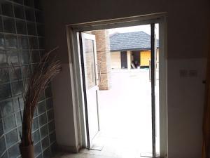 uma porta aberta que leva a um pátio com uma casa em St Theresers apartment Lodge 2 em Lekki