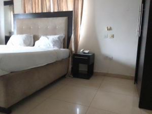 a bedroom with a bed and a phone on a table at St Theresers apartment Lodge 2 in Lekki