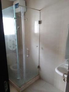 una ducha con una puerta de cristal junto a un lavabo en St Theresers apartment Lodge 2, en Lekki