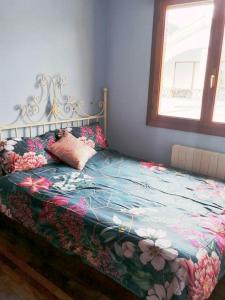 una camera da letto con un letto con una coperta floreale e una finestra di Ampuero, Cantabria, RÍO ASÓN. Hasta 6 personas ad Ampuero