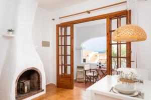 a kitchen with a fireplace and a dining room with a table at Vistafaro in Es Mercadal