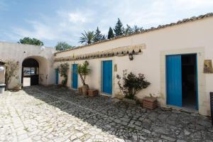 a house with blue doors and a stone driveway at Case Passamonte Agriturismo Resort & Rooms in Chiaramonte Gulfi