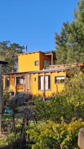 a yellow house sitting in the middle of a yard at Cabañas Bahia Serena in Punta Del Diablo