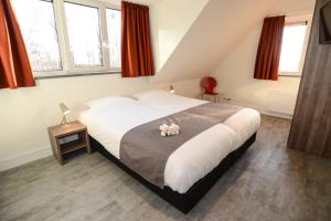 un dormitorio con una cama con un animal de peluche en Razende Bol en De Koog