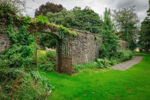 an old stone wall with an arch in a garden at The Rose Cottage in Thomastown