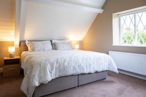 a bedroom with a bed with a white comforter and a window at The Rose Cottage in Thomastown