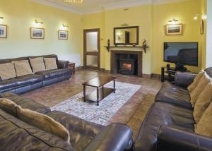 a living room with leather couches and a fireplace at Penbryn Mynach Holiday Cottage in Barmouth
