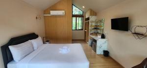 a bedroom with a white bed and a television at Lake Hill Resort Kanchanaburi in Tha Kradan