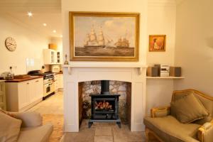 a living room with a fireplace with a painting above it at Old Coastguards - Stunning Historic Cottage in Totland