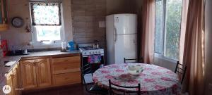 Il comprend une cuisine équipée d'une table et d'un réfrigérateur blanc. dans l'établissement El cahuquen casa 2 dormitorios, à Junín de los Andes