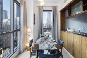 uma sala de jantar com mesa e cadeiras e uma grande janela em Class Home-Superb 1BR apartment with full Burj Khalifa View-5min walk to Dubai Mall em Dubai
