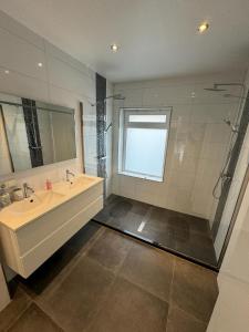 La salle de bains est pourvue d'un lavabo et d'un grand miroir. dans l'établissement Luxurious House in Kerkrade Center, à Kerkrade