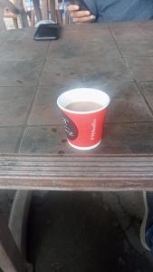 KedārnāthにあるKedarnath Tent Prithvi yatra Hotelの木製テーブルに座ってコーヒーを飲む