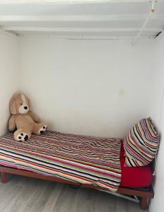 un orsacchiotto seduto su un letto in una stanza di Chambres d'Hôtes Kennedy, Villejean a Rennes