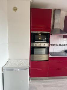 - une cuisine avec des placards rouges et une cuisinière dans l'établissement Chambres d'Hôtes Kennedy, Villejean, à Rennes