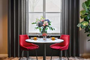ESPLANADE Saarbrücken في ساربروكن: طاولة مع كراسي حمراء و إناء من الزهور