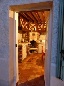 une porte ouverte menant à une cuisine équipée d'une cuisinière dans l'établissement Maison d'hôtes La Source, à Magny-les-Hameaux