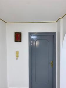un couloir avec une porte bleue et une photo sur le mur dans l'établissement Appartement au cœur du ville, à Tanger