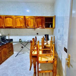 - une cuisine avec des placards en bois, une table et des chaises dans l'établissement Appartement au cœur du ville, à Tanger
