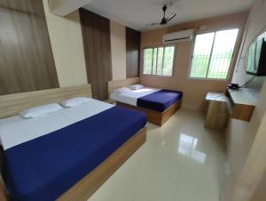 a bedroom with two beds and a tv in it at Shree lodge in Dandeli