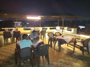 two people sitting at tables in a restaurant at night at Hotel Kamal Agra in Agra