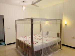 a bedroom with a canopy bed with flowers on it at Hari Hari Arugambay in Arugam Bay