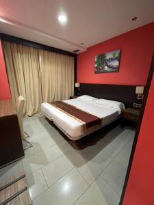 a bedroom with a large bed with a red wall at Hotel Ruta Romana in Sagunto