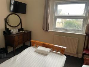 a bedroom with a bed and a mirror and a window at Heathrow Stay in Hounslow