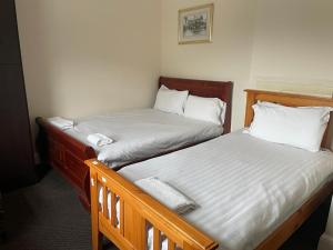 two twin beds in a small room withermottermottermott at Heathrow Stay in Hounslow