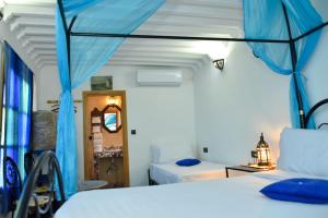 1 dormitorio con 2 camas con cortinas azules en Riad Fes EL KAID, en Fez