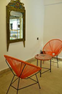 2 chaises orange, une table et un miroir dans l'établissement Riad Fes EL KAID, à Fès