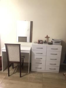 a white desk with a chair and a dresser at Quarto privativo Sanilda in Vitória