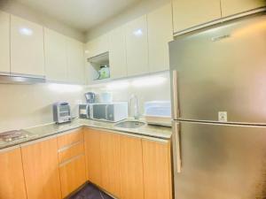 a kitchen with wooden cabinets and a stainless steel refrigerator at The mactan Newtwon Near Airport with POOL&BEACH access in Punta Engaño