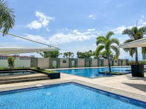 a large swimming pool with palm trees and a building at The mactan Newtwon Near Airport with POOL&BEACH access in Punta Engaño