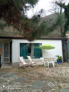 a patio with a table and chairs and an umbrella at Un 'Oasi nel verde ad un passo da tutto in San Felice a Cancello
