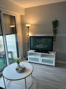 uma sala de estar com uma televisão e uma mesa em Chambres d'Hôtes Kennedy, Villejean em Rennes