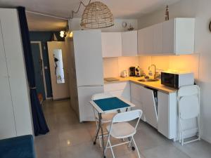 uma cozinha com armários brancos e uma mesa e cadeiras em Studio port et mer em Le Grau-du-Roi