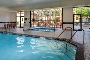 a swimming pool with tables and chairs in a building at Courtyard Des Moines West/Clive in Clive