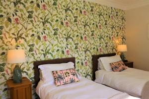 2 camas en una habitación con papel pintado floral en Portclew House en Pembroke