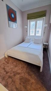 a bedroom with a large white bed with two windows at Krakowskie Przedmieście "Night and Day" in Warsaw