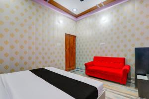 1 dormitorio con 1 cama y 1 silla roja en OYO C.M Paradise, en Lucknow