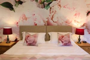 ペンブロークにあるPortclew Houseのベッドルーム1室(ピンクの花が飾られた壁のベッド1台付)