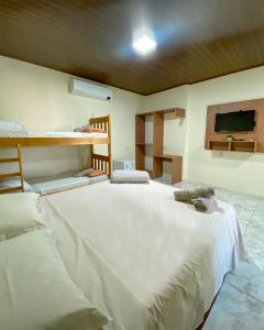 a large white bed in a room with a tv at Bonito Suítes in Bonito