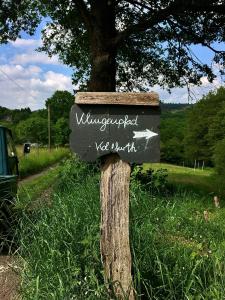 a sign attached to a tree in the grass at Ökologisches und modernes Waldhäuschen in Solingen